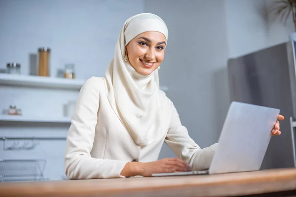 美丽的年轻穆斯林妇女使用笔记本电脑和微笑着在相机 — 图库照片
