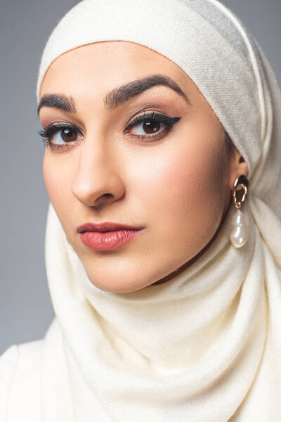 portrait of beautiful young muslim woman looking at camera isolated on grey 