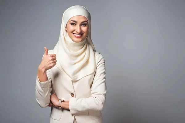 Молода Мусульманка Посміхається Камеру Показує Великий Палець Ізольовано Сірому — стокове фото