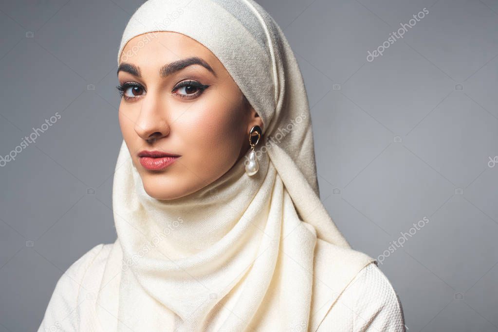 portrait of beautiful young muslim woman looking at camera isolated on grey