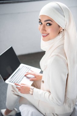 dizüstü bilgisayar ile boş ekran kullanarak ve kameraya gülümseyen güzel Müslüman kadın 
