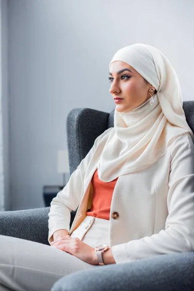 沉思的年轻穆斯林妇女坐在椅子上 看着离开 — 图库照片