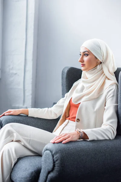 young muslim woman sitting in chair and looking away