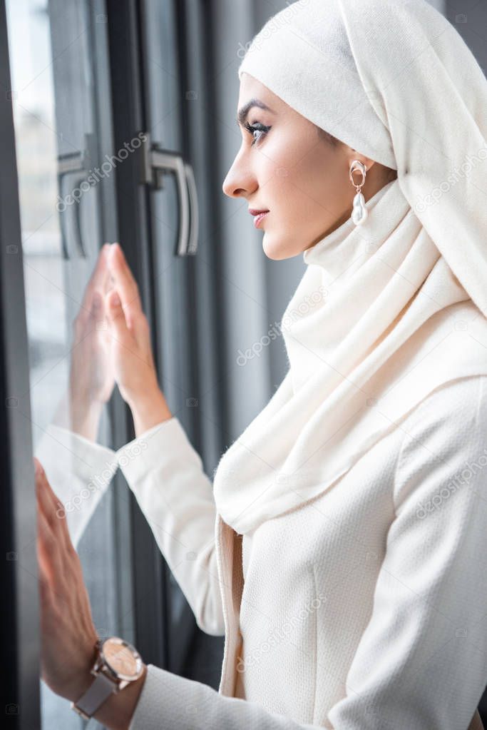 side view of young muslim woman looking at window 