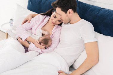 Genç anne emzirme evde yatakta kocası ile küçük bebek