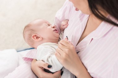 Anne küçük ağlayan bebek sakinleştirici kısmi görünümünü ellerinde