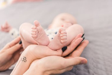 partial view of mother and father holding babys feet together clipart