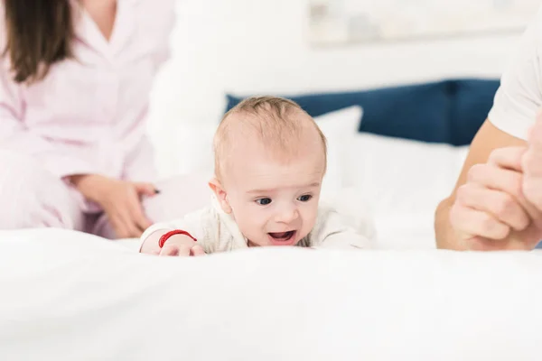 親と家庭で一緒にベッドの上に横たわる小さな赤ちゃんの部分的なビュー — ストック写真