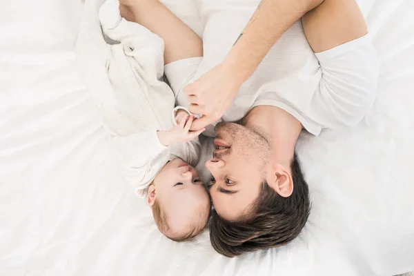 若い父親と家庭で一緒にベッドの上に横たわる小さな赤ちゃんのオーバー ヘッド ビュー — ストック写真