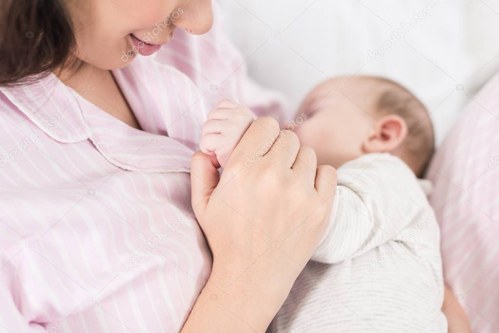 partial view of cute baby sleeping on mothers hands