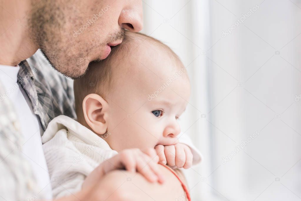 partial view of father holding little son in hands
