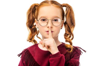 adorable child in glasses showing hush gesture and looking at camera isolated on white clipart