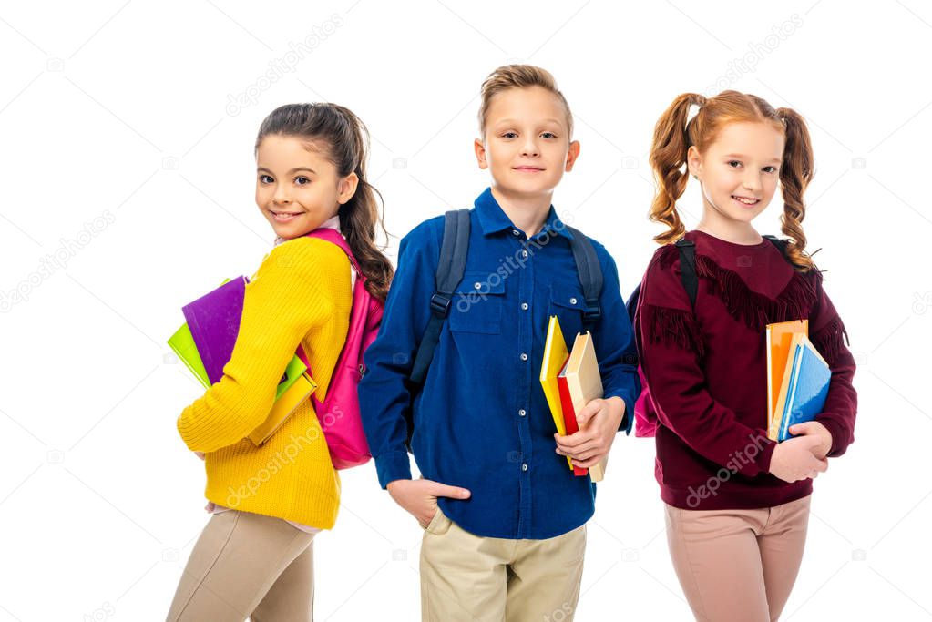 schoolchildren with backpacks holding books isolated on white