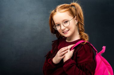 siyah arka plan üzerine kameraya bakarak pembe sırt çantası ile gözlük kız öğrenci gülümseyen