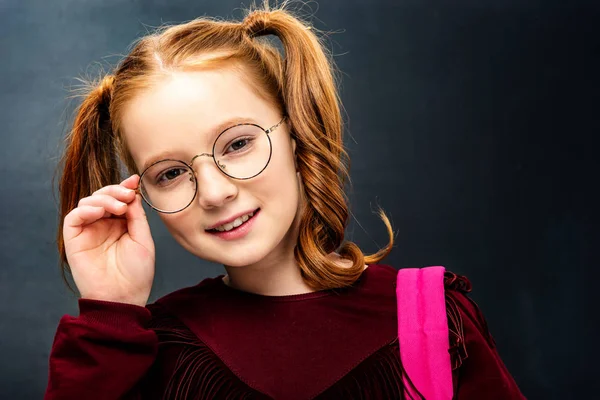 Nettes Schulmädchen Das Brille Berührt Und Kamera Auf Schwarzem Hintergrund — Stockfoto