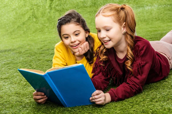 Cheerful Schoolgirls Lying Lawn Reading Book — Stock Photo, Image