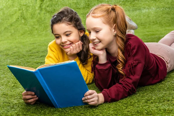 Smiling Schoolgirls Lying Lawn Reading Book — Stock Photo, Image