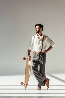 yakışıklı longboard gri arka plan üzerinde tutan adam sakallı