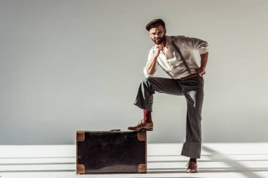 yakışıklı adam gözlük ve retro çanta gri arka plan üzerinde kameraya bakarak yakın kap