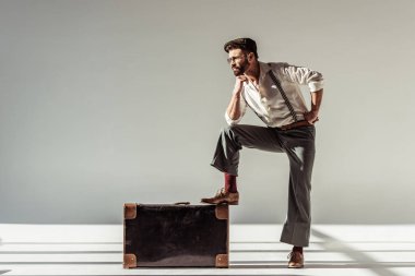 sakallı adam gözlük ve kap vintage çanta kameraya gri arka plan üzerinde seyir
