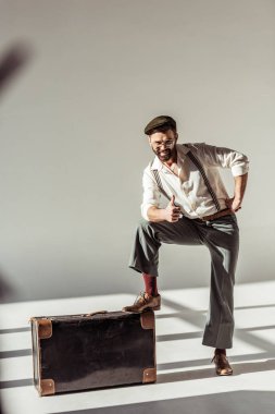sakallı adam başparmak gösterilmesini ve gri arka plan üzerinde kameraya bakarak vintage çanta