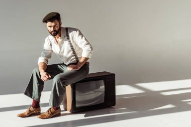 yakışıklı şık sakallı adam oturuyor vintage tv ve kameraya bakıyor