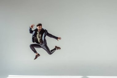 bearded man in cap and glasses jumping high on grey background clipart