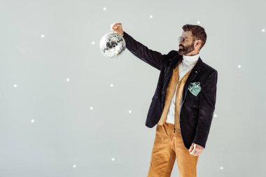 sakallı yakışıklı gri arka plan üzerinde elinde bir disko topu bakıyor