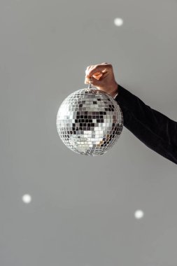 cropped view of man holding disco ball on grey background clipart