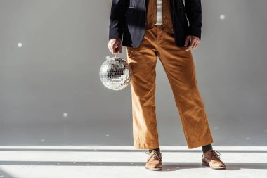 cropped view of man holding mirror ball on grey background clipart