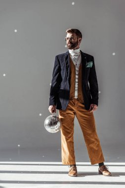 disko topu tutarak ve gri arka plan üzerinde poz yakışıklı adam