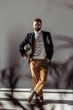 seçici odak sakallı adam mozaik disko topu tutan ve kameraya gri arka plan üzerinde seyir