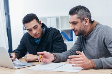 Erkek arkadaşları çalışma kağıtları ve office içinde laptop ile konsantre