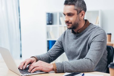 yakışıklı gülümseyen dizüstü Office ile çalışan işadamı sakallı
