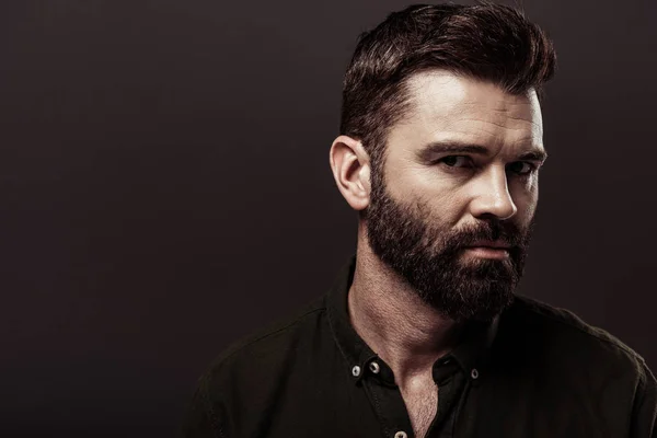 handsome bearded man in brown shirt looking at camera isolated on brown