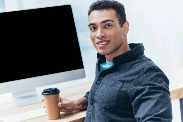 デスクトップ コンピューターを使用してカメラに笑顔コーヒーと青年実業家 — ストック写真