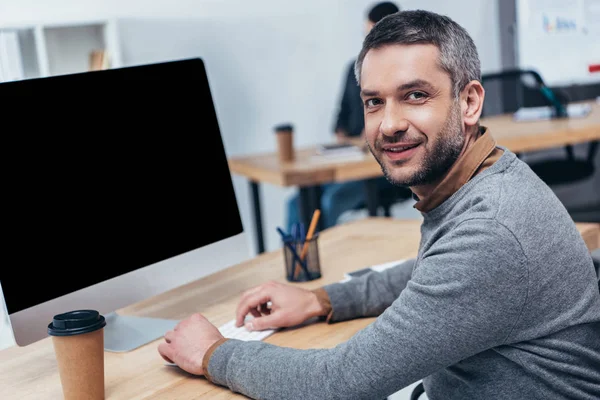 ハンサムなひげを生やしたデスクトップ コンピューターでの作業 オフィスでカメラで笑顔の実業家 — ストック写真