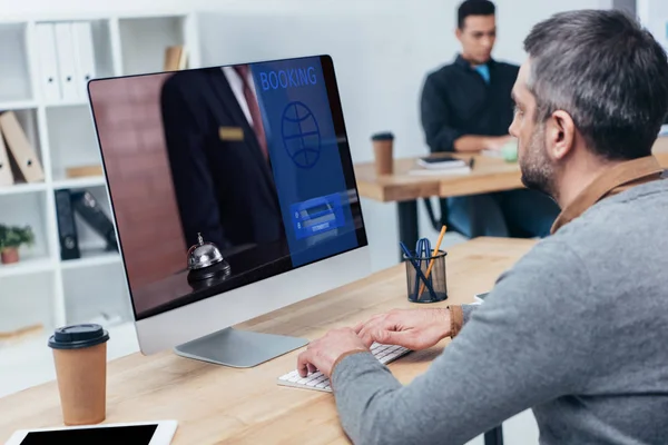 商人使用台式电脑与预订网站在屏幕上在办公室 — 图库照片