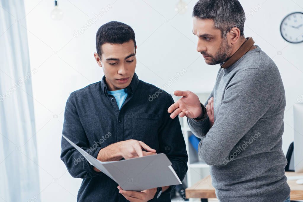 businessmen working with folder and discussing project in office