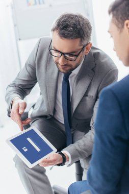 Dijital tablet facebook app ile Office erkek meslektaşı ekranda gösteren gözlük işadamı kadeh kırpılmış