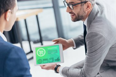 Erkek meslektaşı Office dijital tablet alışveriş app ekran ile gösterilen gözlük işadamı kadeh kırpılmış