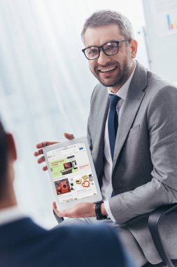işadamı dijital tablet ebay uygulama ile ekran üzerinde tutarak gözlük gülümseyen
