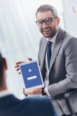 işadamı dijital tablet facebook app ile ekran üzerinde tutarak gözlük gülümseyen