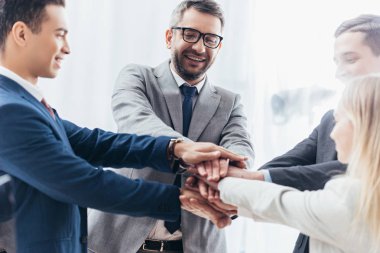 happy business team stacking hands in office  clipart