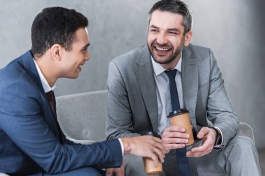 Kağıt bardak kahve içme ve birlikte konuşurken neşeli işadamları