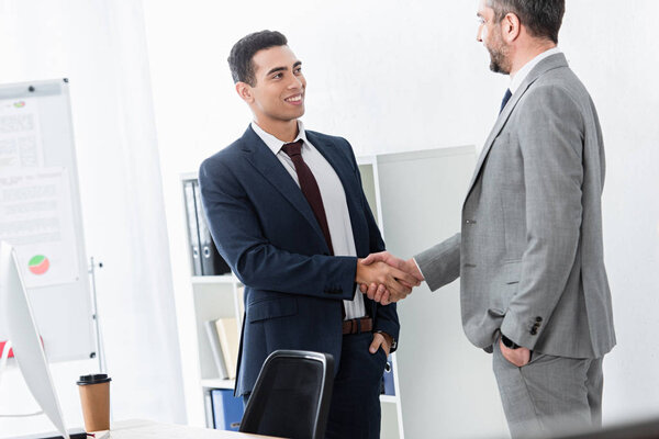 professional businessman in formal wear shaking hands and smiling each other in office  