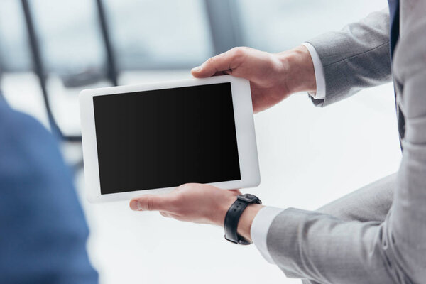 partial view of businessman holding digital tablet with blank screen