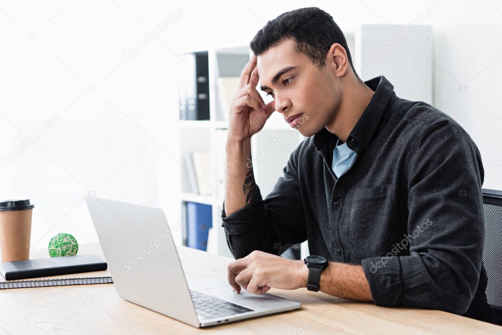 serious concentrated young businessman working with laptop in office 