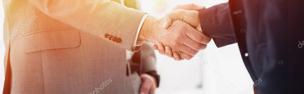 close-up partial view of businessmen in formal wear shaking hands in office  