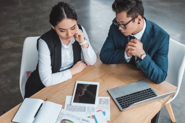 çalışma kağıtları ve Office dijital cihazlar ile genç kazak iş arkadaşları yüksek açılı görünüş
